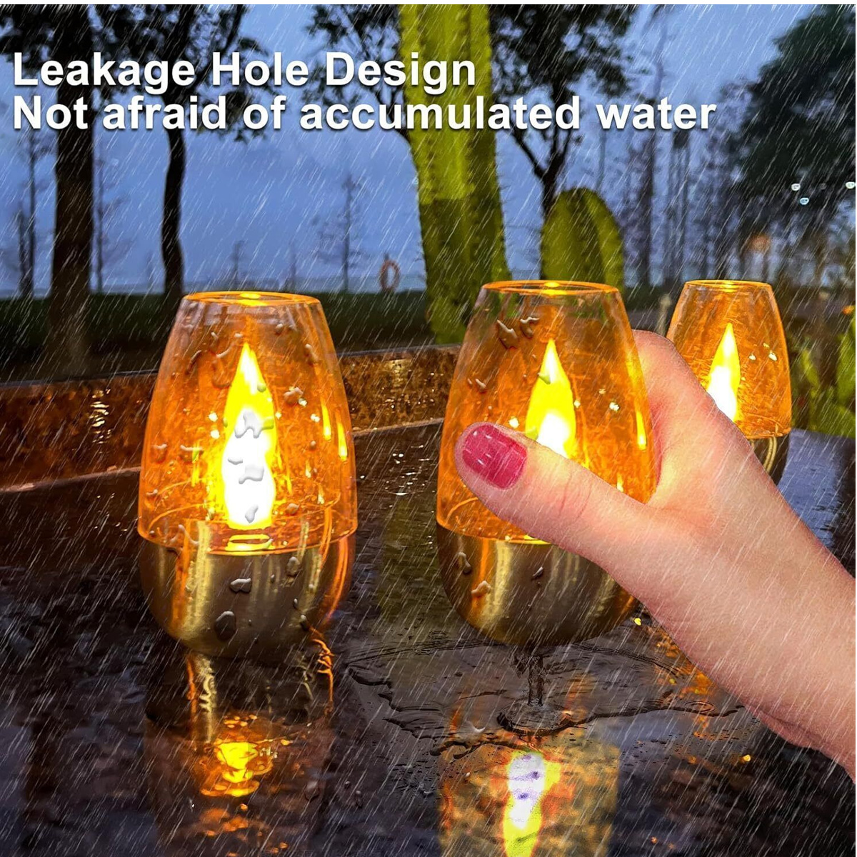 Ein Mensch berührt eine von mehreren goldenen Kerzen mit Flammeneffekt im Regen.