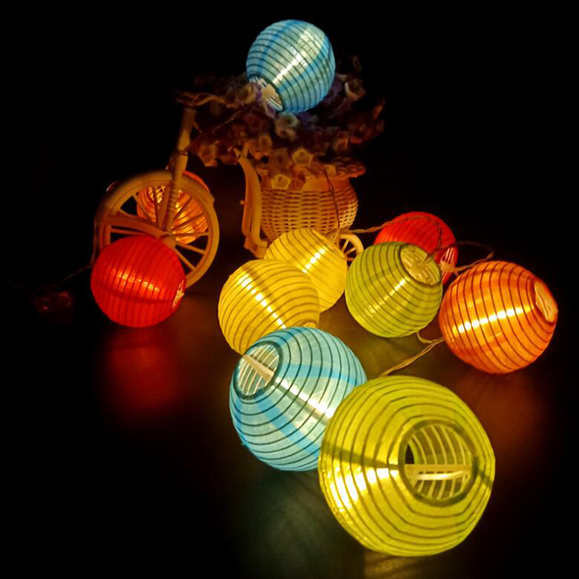 Bunte Lichterketten in Form von Papierlaternen, die auf einem dunklen Hintergrund leuchten.