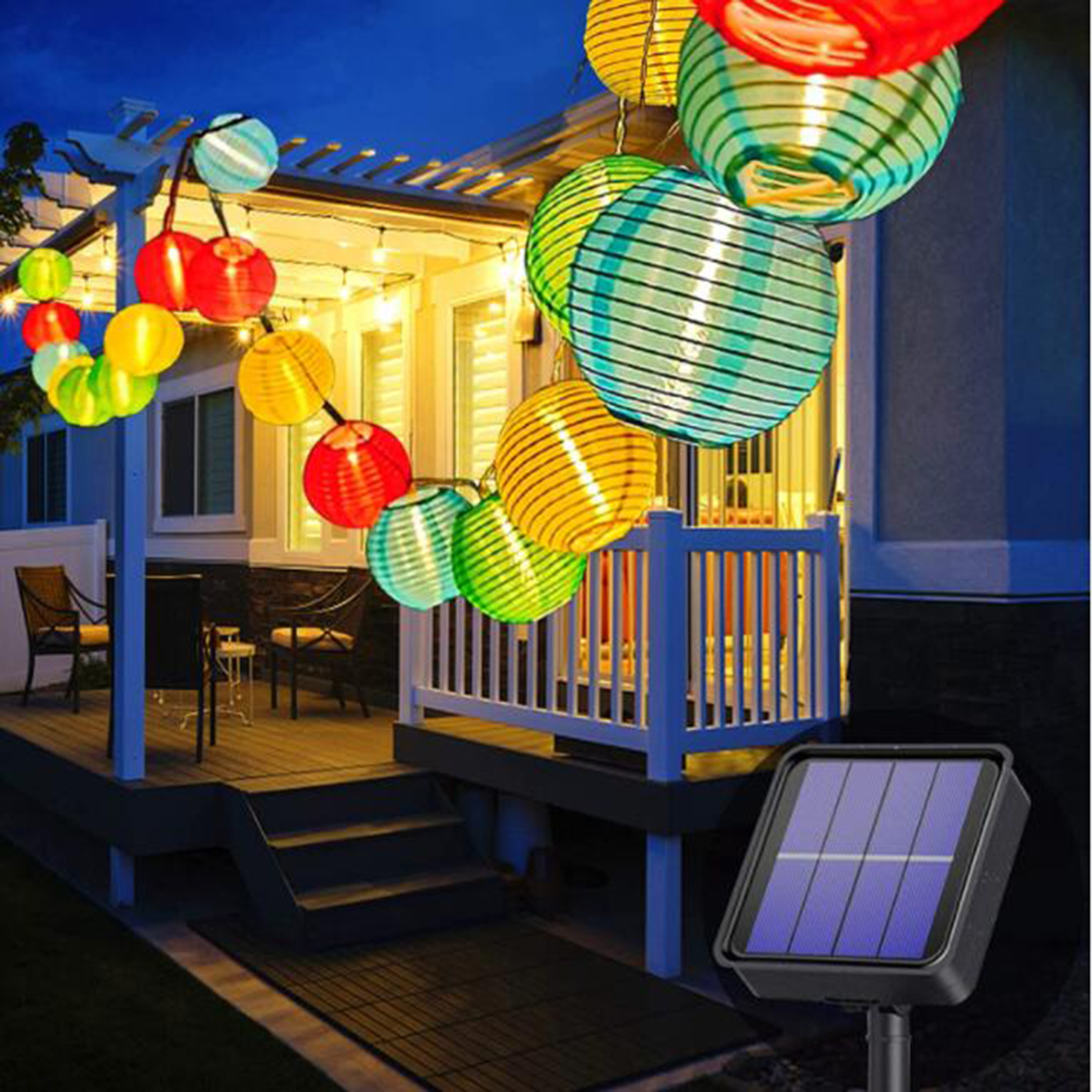 Bunte Lampions beleuchten eine Veranda mit Möbeln und Solarmodul.