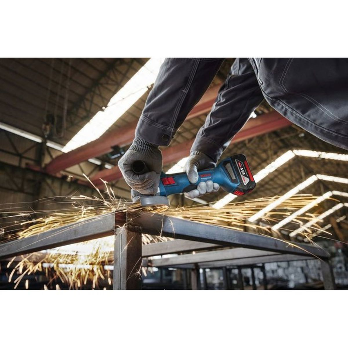 Ein Handwerker schleift Metall mit einem blauen Winkelschleifer, Funken fliegen.