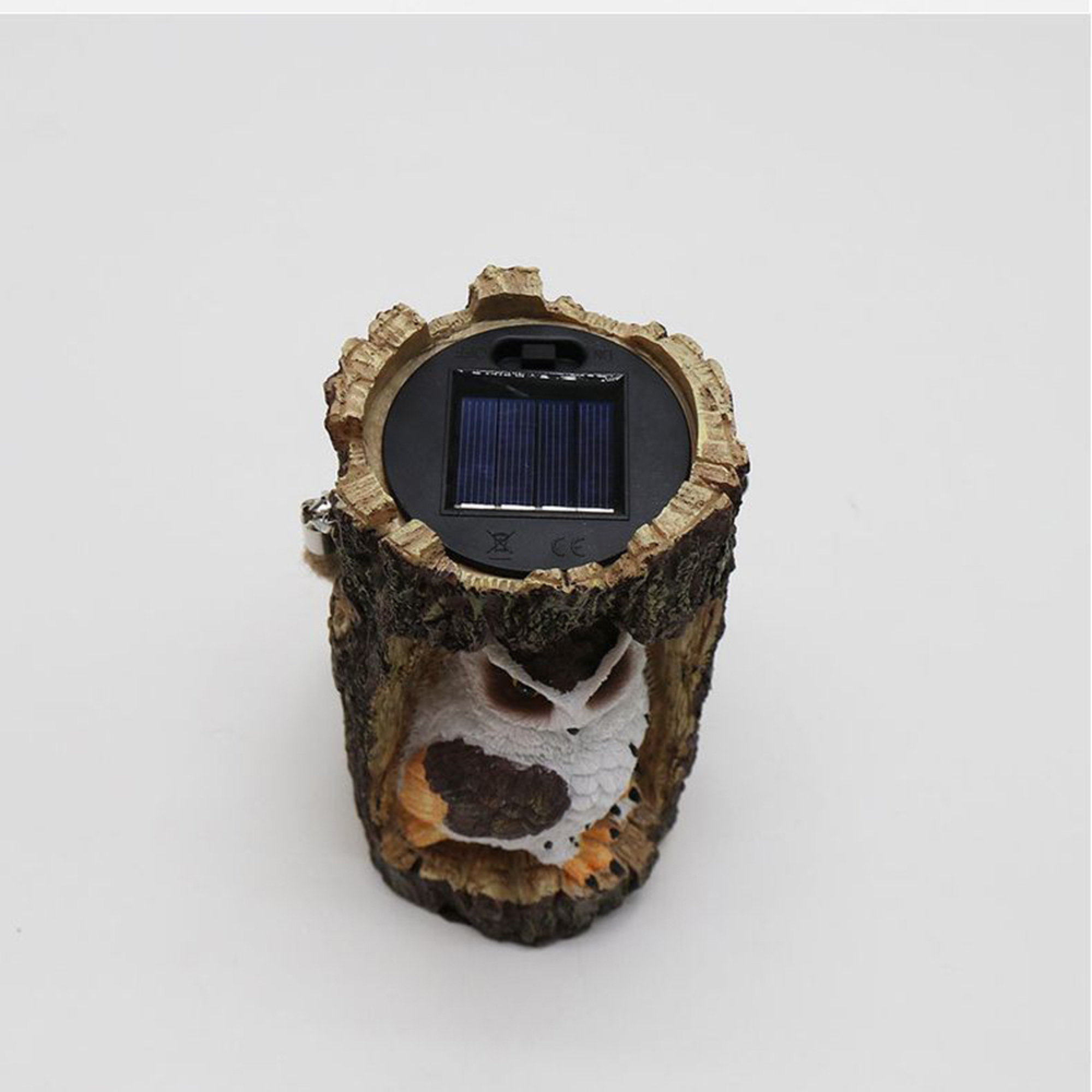 Eine Eule, die in einem Baumstamm sitzt, mit einem Solarpanel oben.