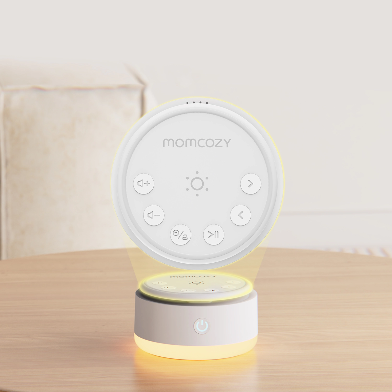 Een wit Momcozy apparaat met bedieningselementen en geel licht op een houten tafel.