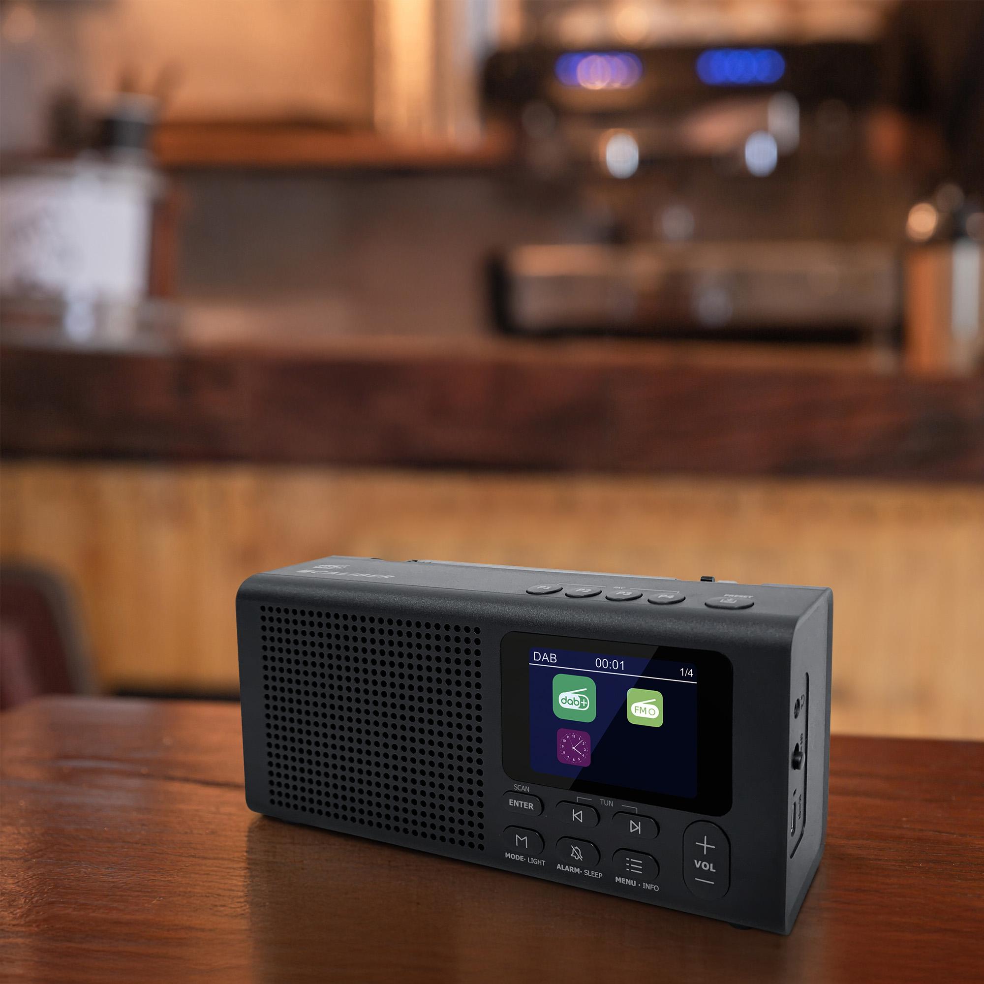 Ein schwarzer DAB-Radio mit Bildschirm steht auf einem Holztisch.