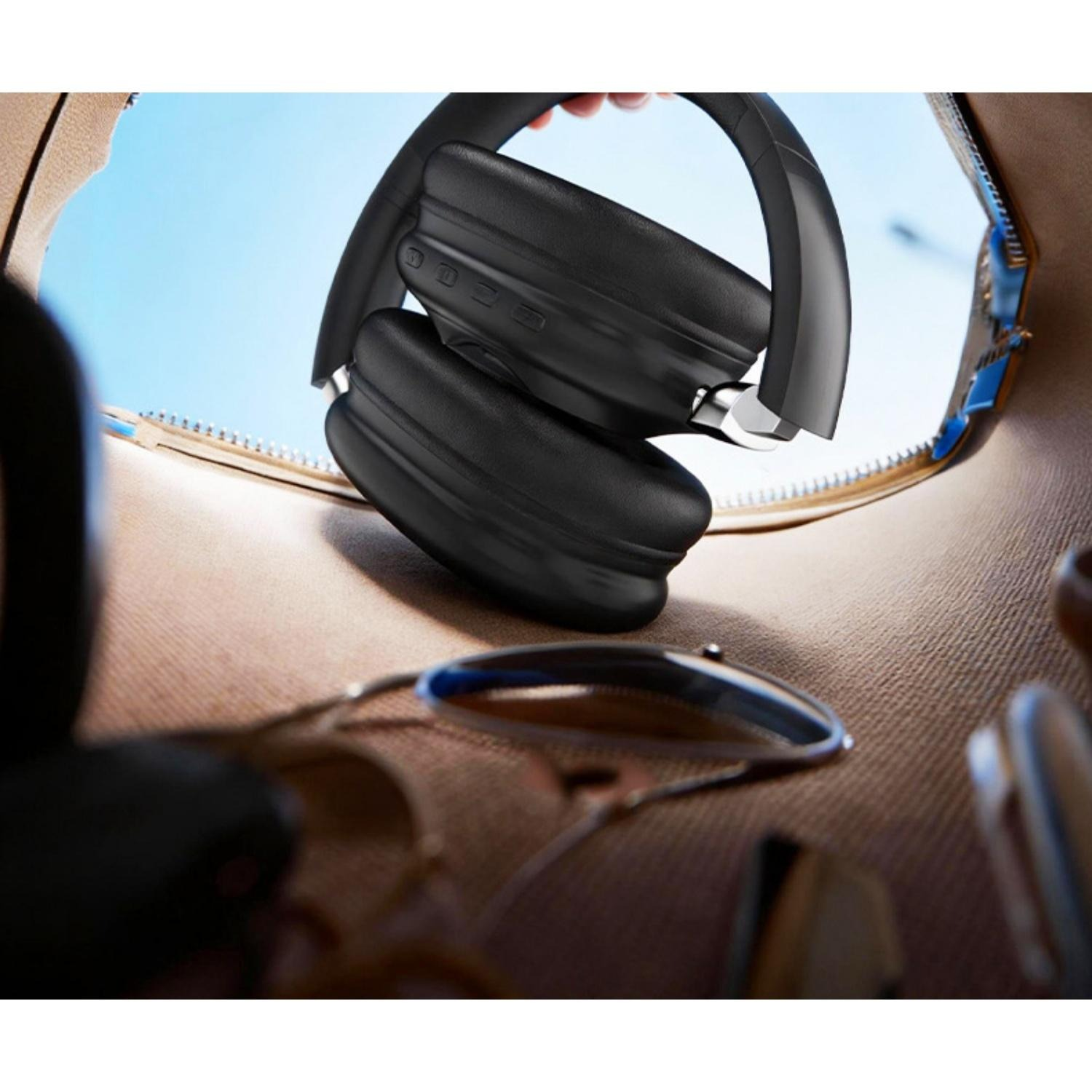 Schwarze Kopfhörer werden in eine Tasche gelegt, Sonnenbrille liegt daneben.