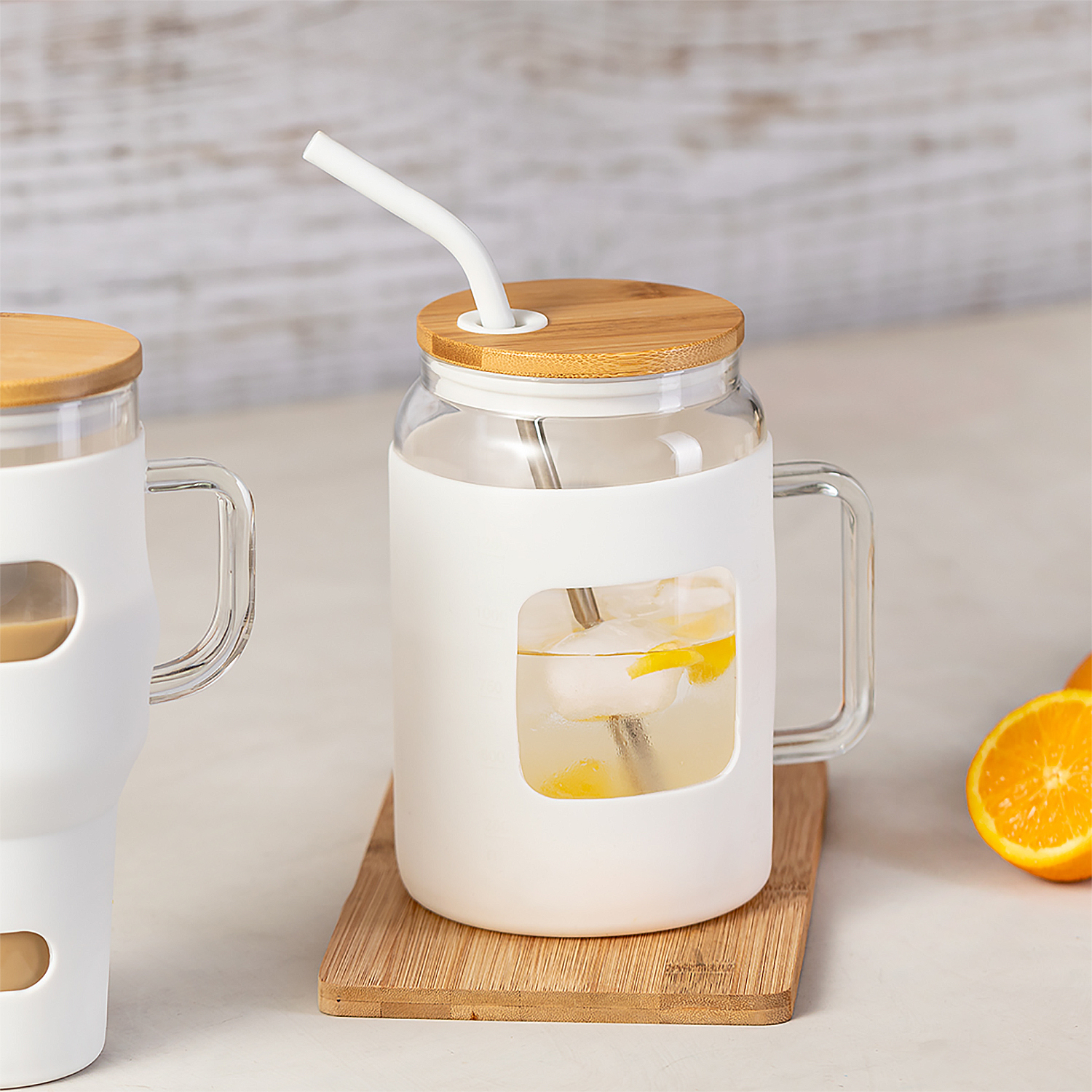 Una tazza di vetro con manicotto bianco, coperchio in legno, cannuccia e fettine di limone.