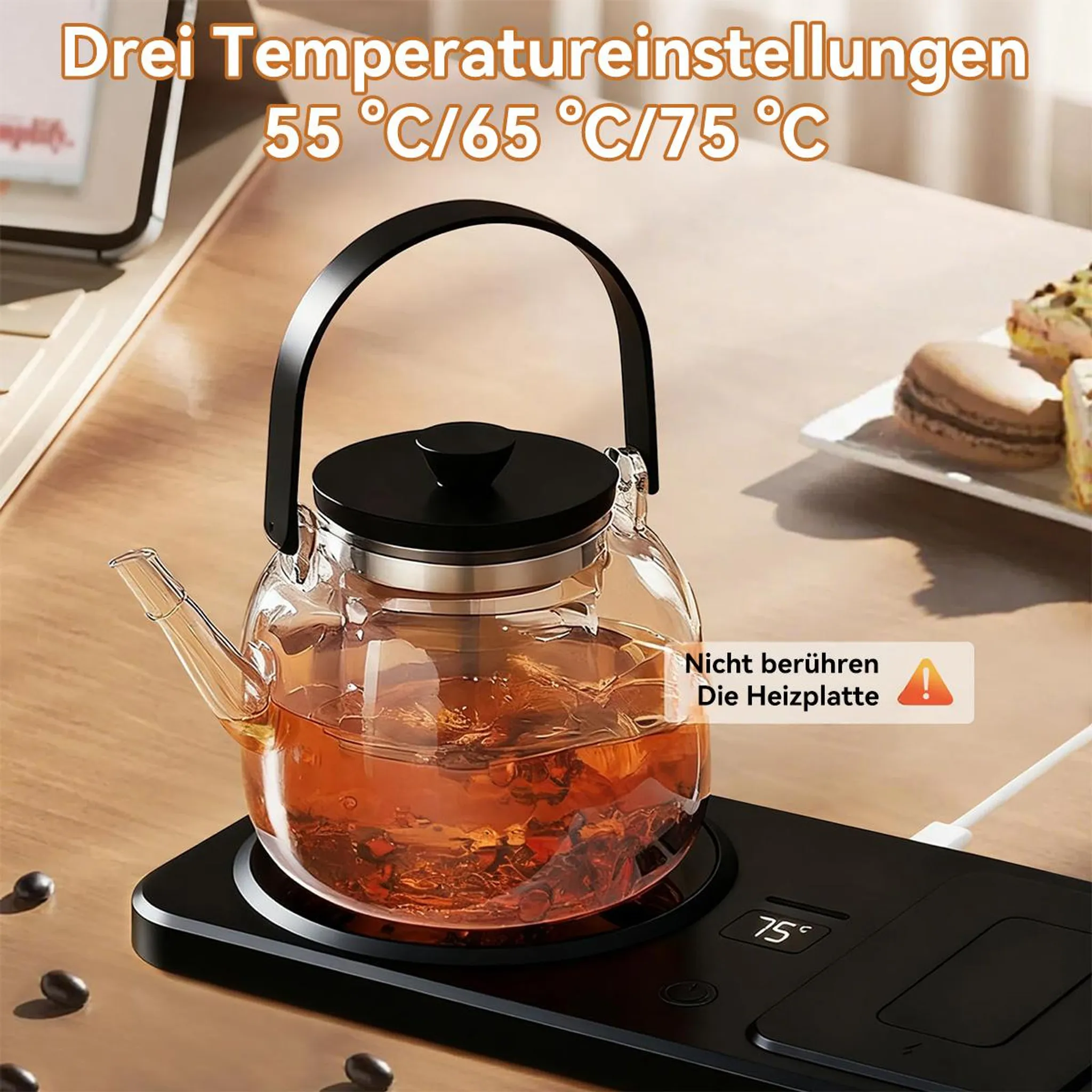 Glas-Teekanne auf schwarzer Heizplatte mit 75°C Anzeige. Macarons im Hintergrund.