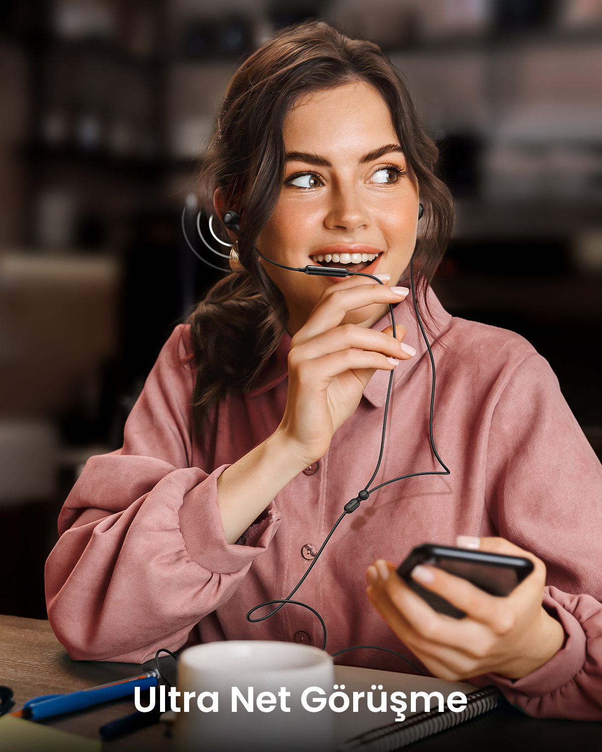 Kulaklık ve mikrofon takan kadın elinde bir akıllı telefon tutuyor.