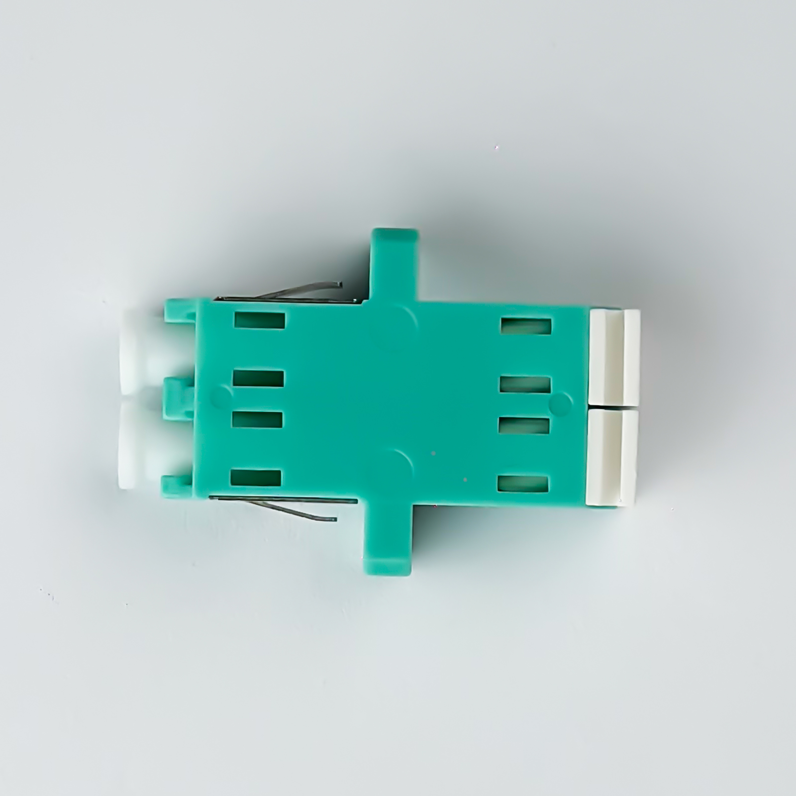 Ein türkiser Stecker mit weißen Enden und Metallstiften auf weißem Grund.