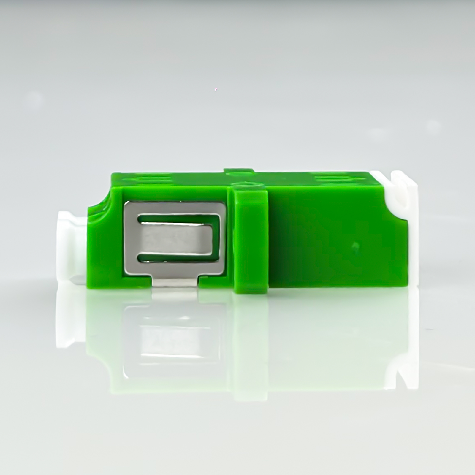 Grünes medizinisches Gerät mit silbernem Mechanismus auf reflektierender Oberfläche.