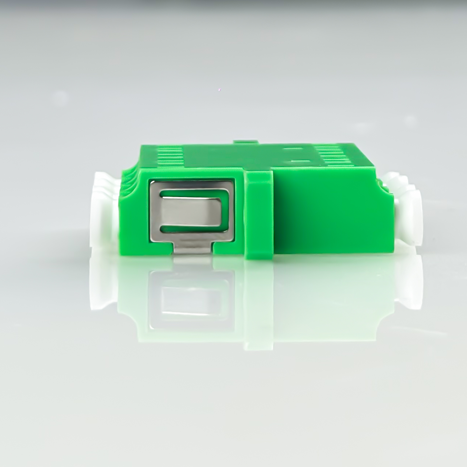Grüner Stecker mit silbernem Klemmmechanismus, weißer Anschluss.
