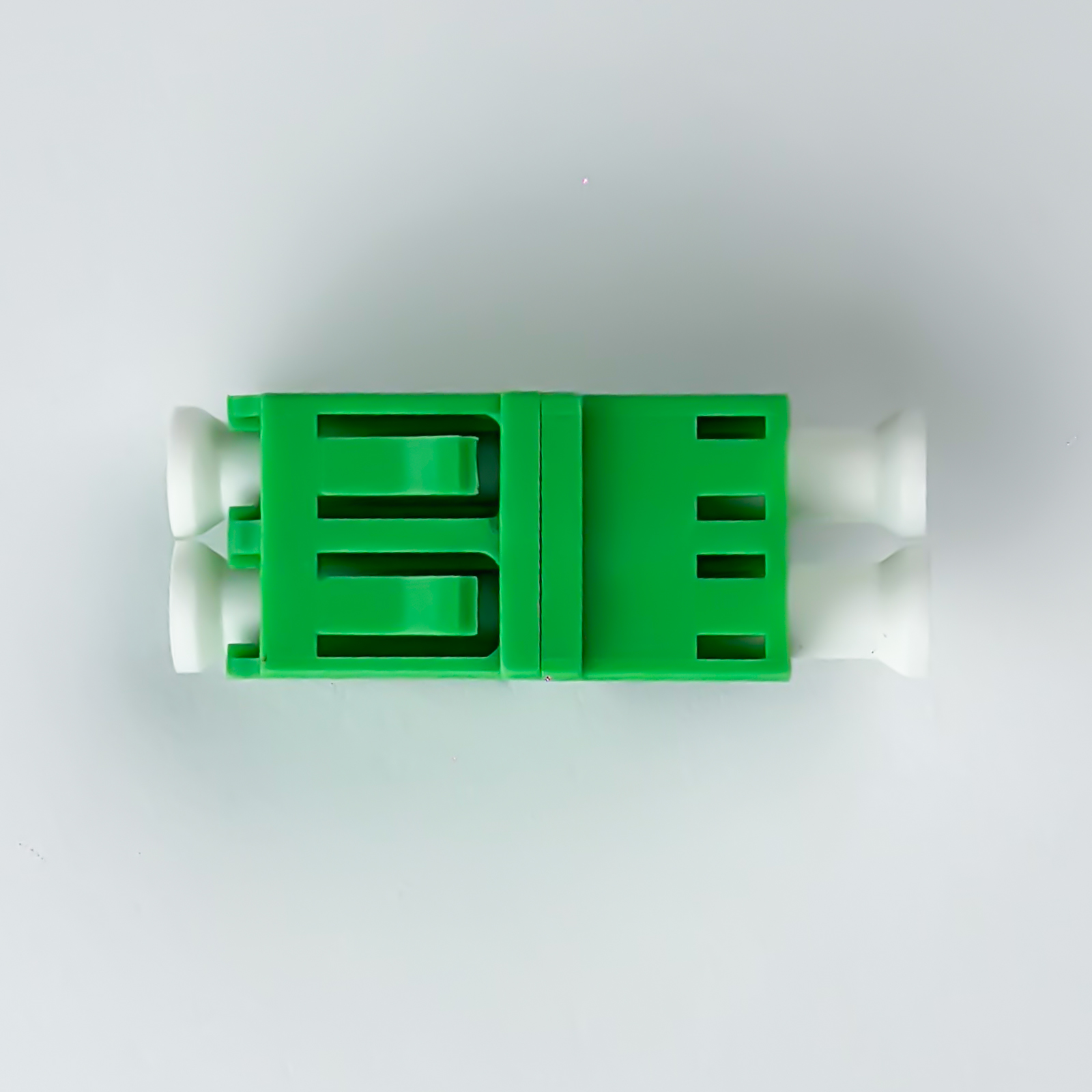Ein grüner und weißer Stecker, auf weißem Hintergrund liegend.