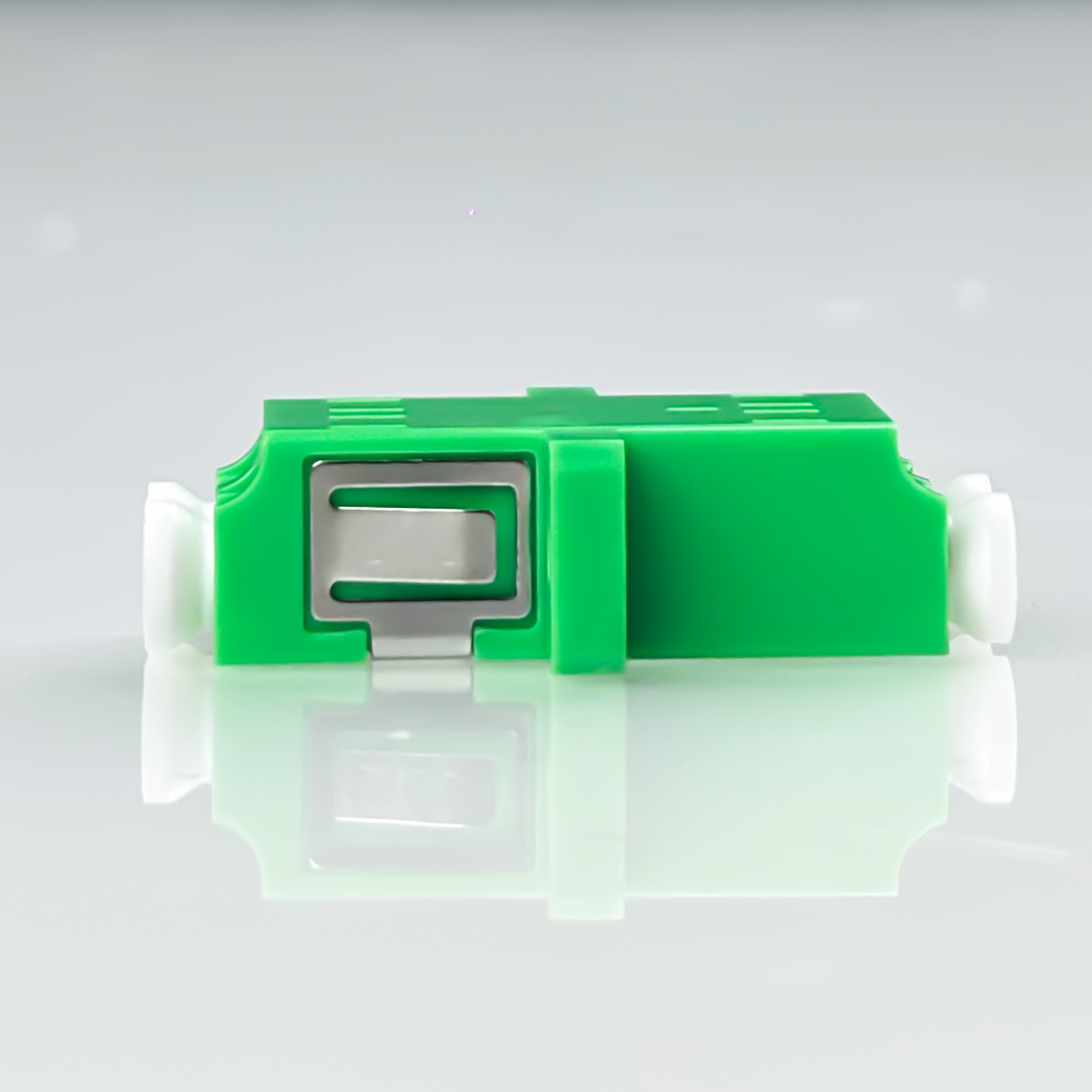 Ein grüner Stecker mit silbernen Metallteilen und weißen Enden.