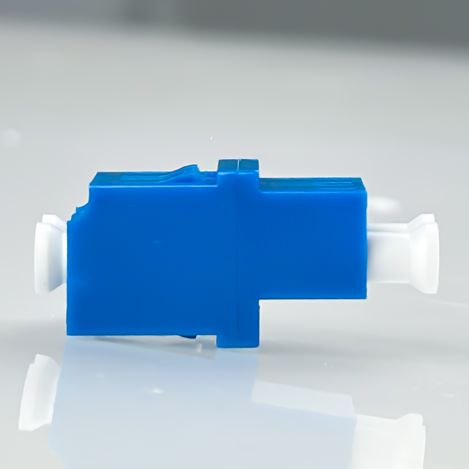 Ein blaues und weißes Glasfaser-Adapter-Gehäuse auf hellem Hintergrund.