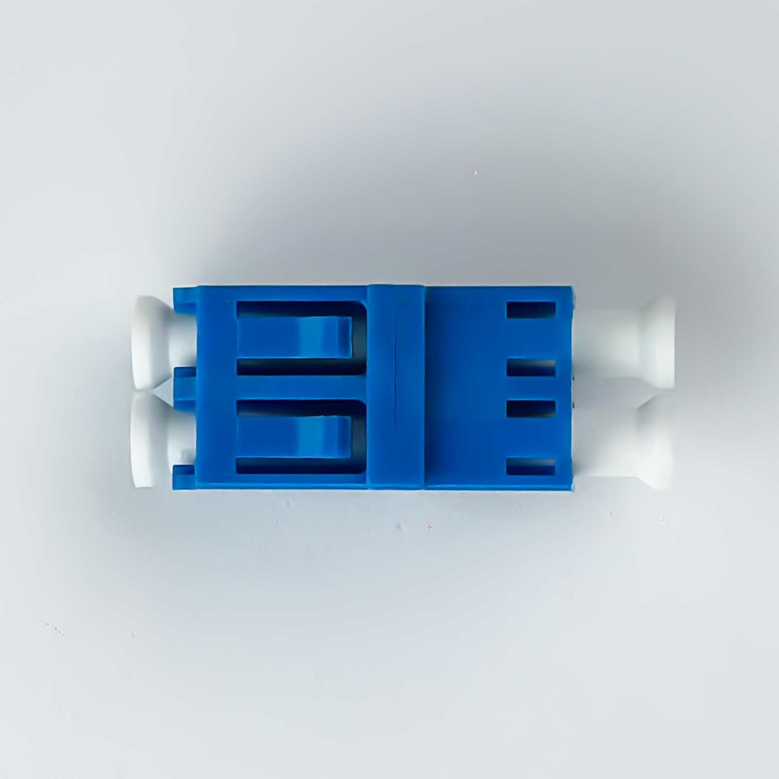 Ein blauer und weißer Stecker für Glasfaserkabel auf weißem Hintergrund.