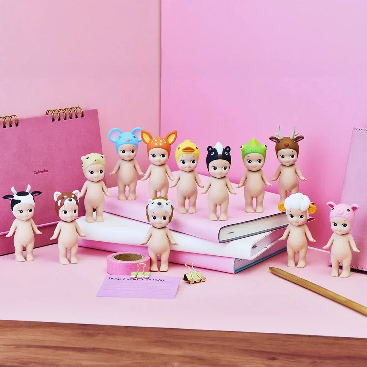 Zehn süße Figuren mit Tierkopfbedeckungen stehen auf Büchern und einem Schreibtisch.