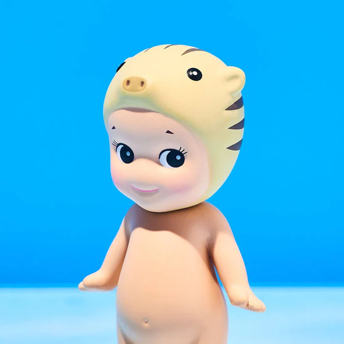 Ein Baby-Figur mit gelbem Tigerhut und blauen Hintergrund.