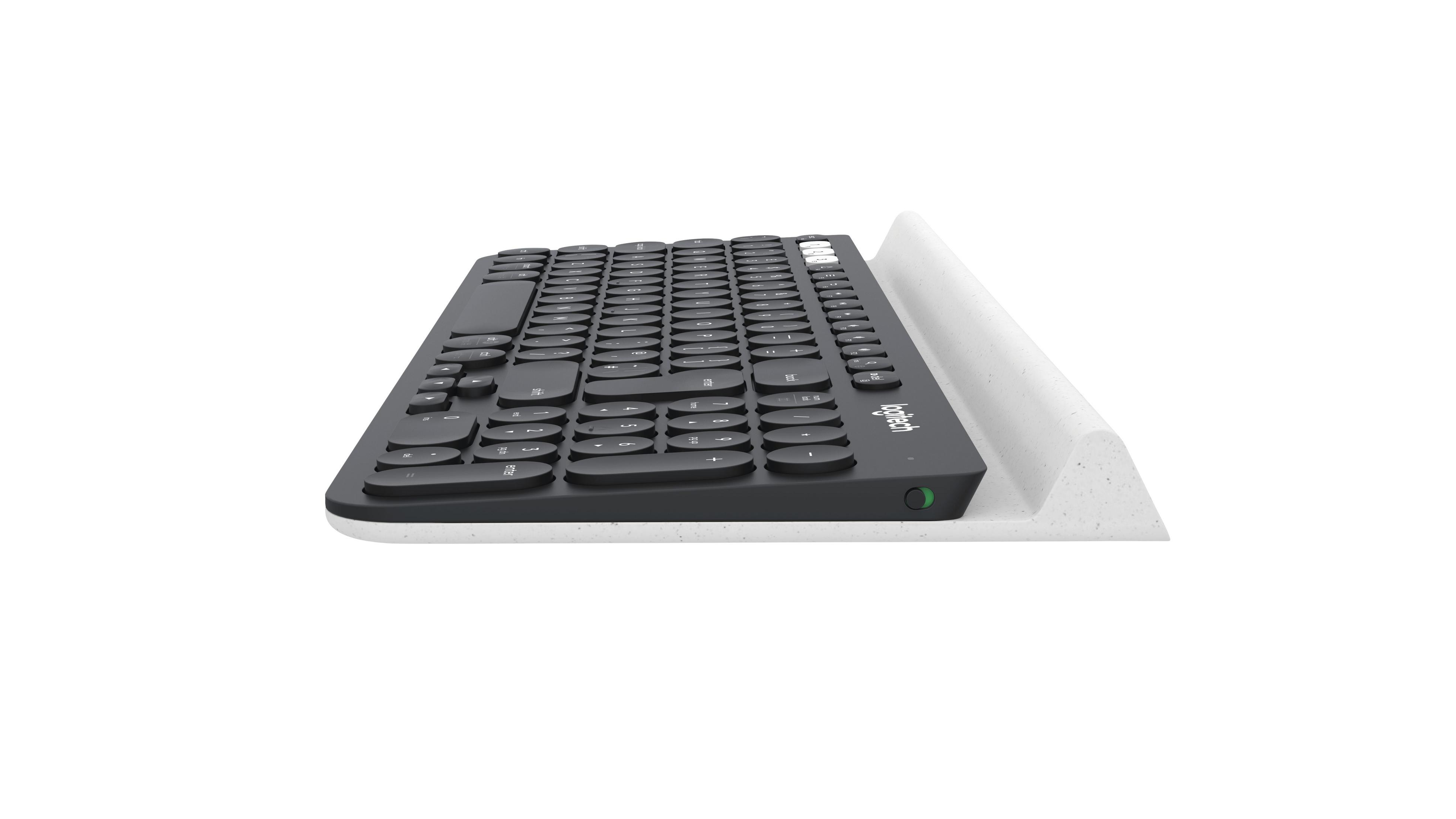 Una tastiera Logitech nera su un supporto bianco, vista laterale.