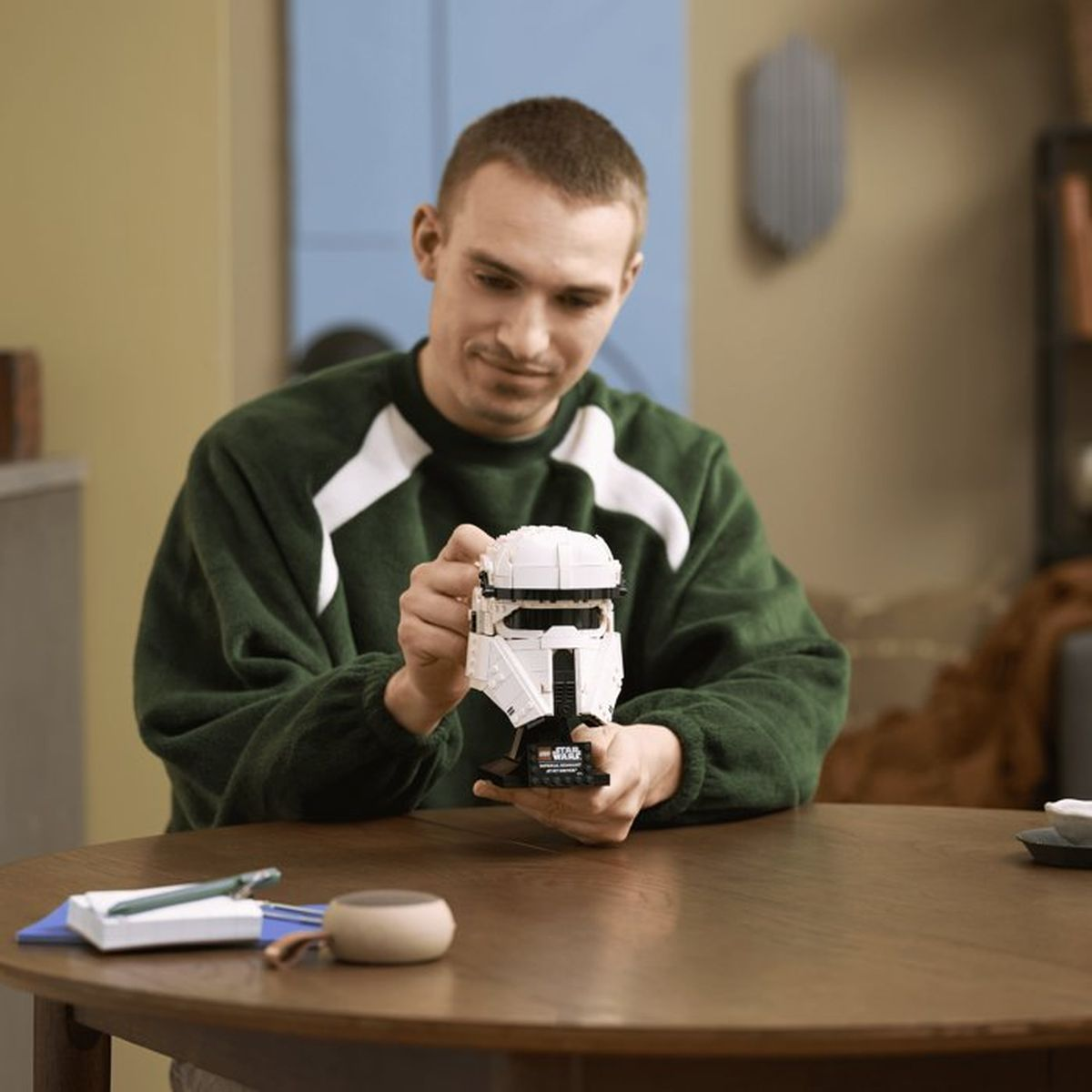 Uomo in maglione verde tiene un elmo bianco Lego di Stormtrooper.