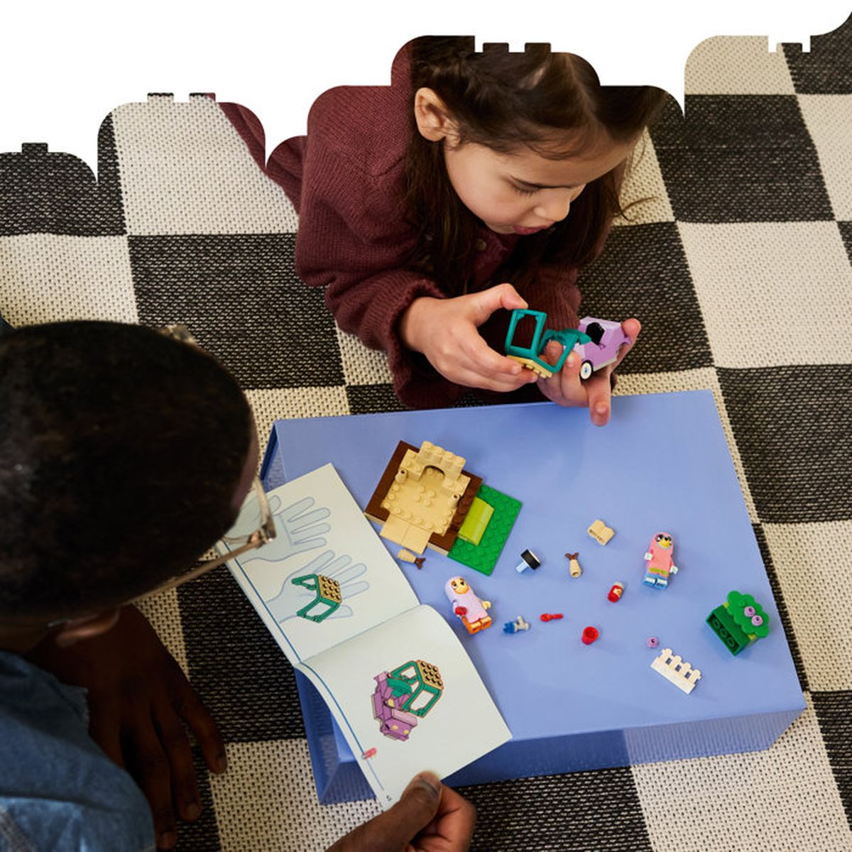 Bambini costruiscono con blocchi colorati su un vassoio blu e un tappeto a scacchi.