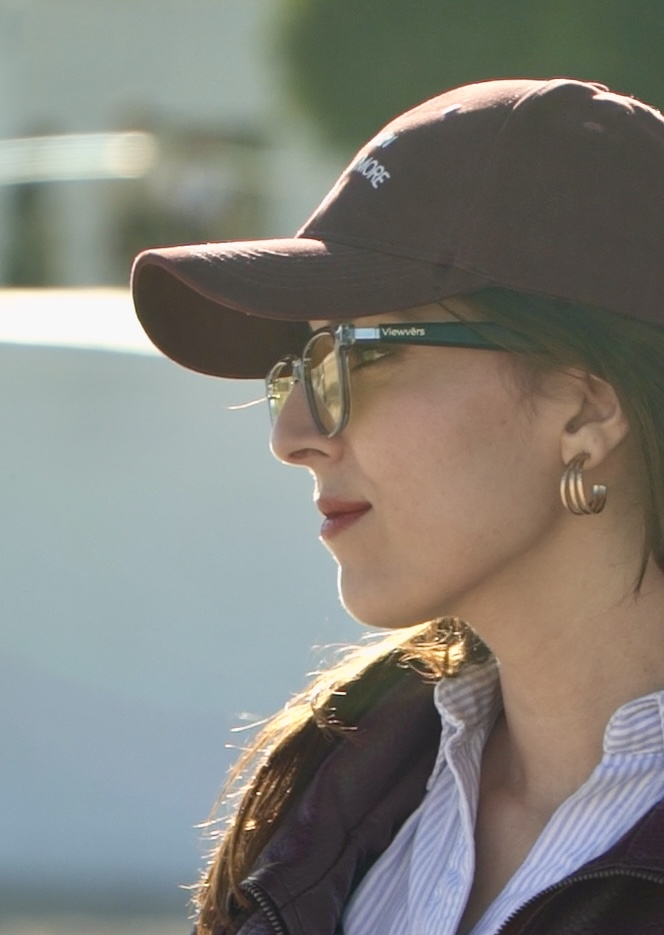 Mujer con gorra granate y gafas de sol, de perfil.