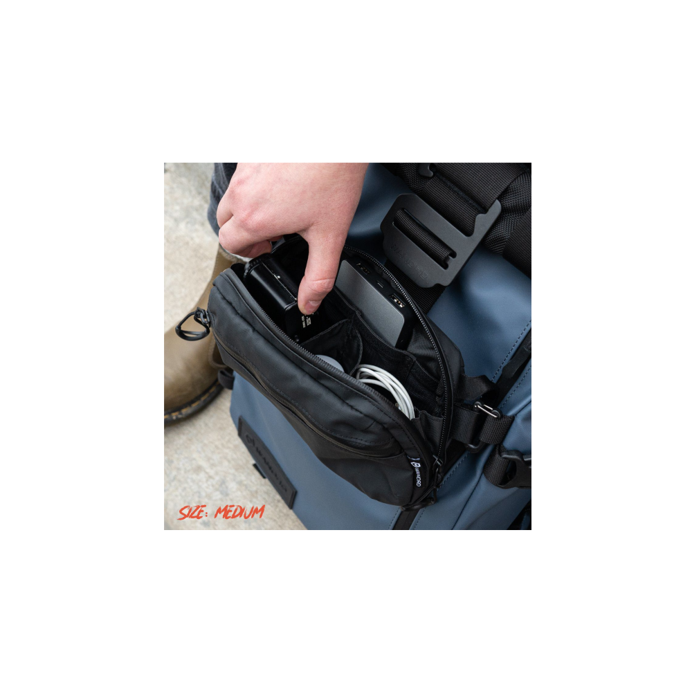 A hand places a black item into an open black bag on a blue backpack.
