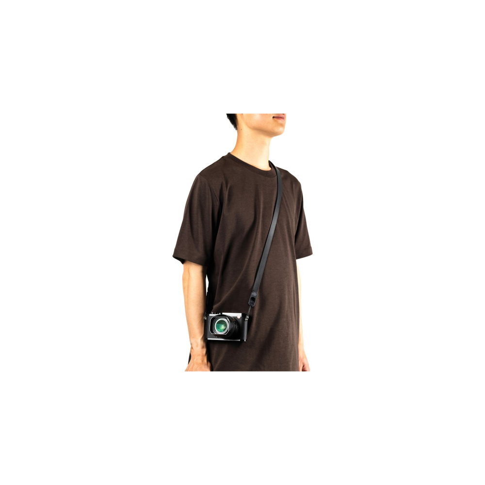 Man in bruin T-shirt draagt een zwarte camera met riem.