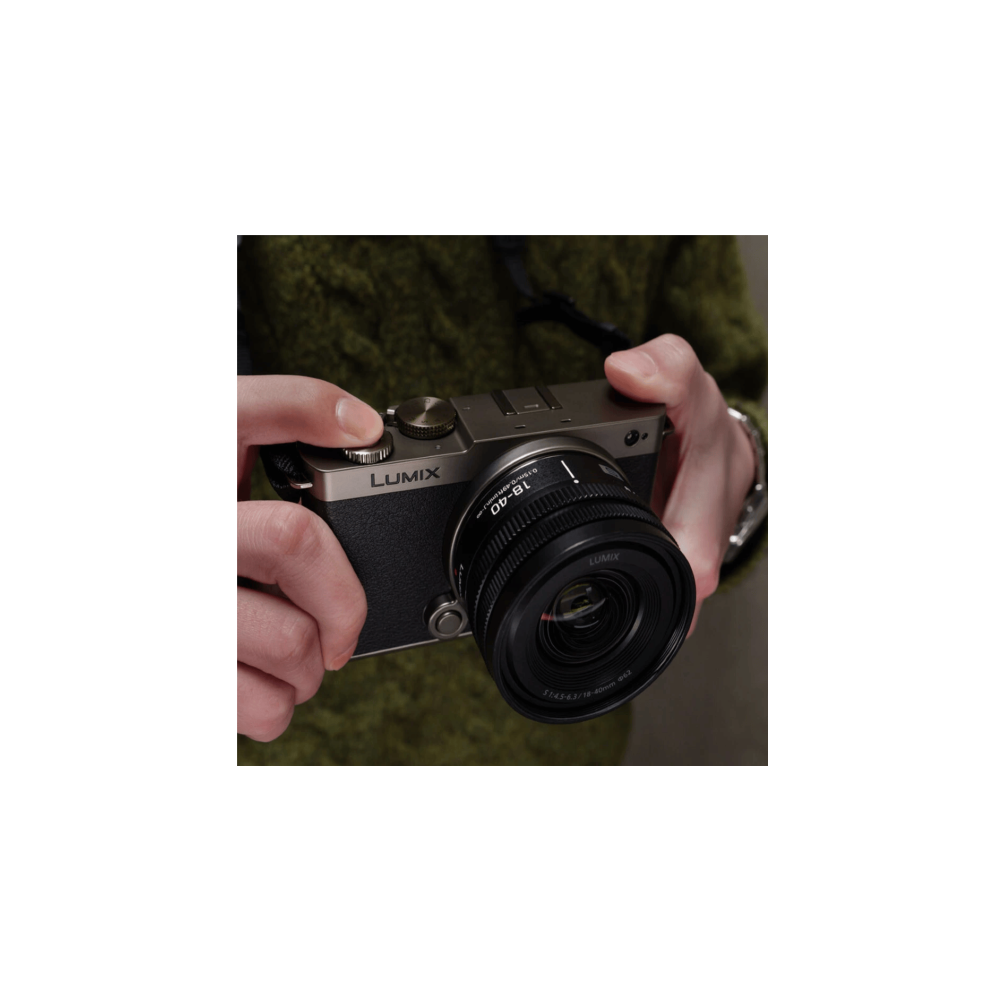 Grijze Lumix camera met lens, vastgehouden door handen in een groen vest.