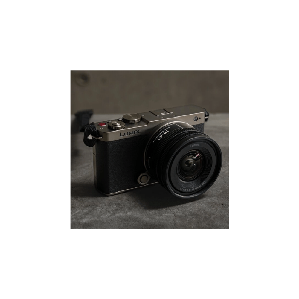 Een zilveren en zwarte Lumix camera met lens op een grijze ondergrond.