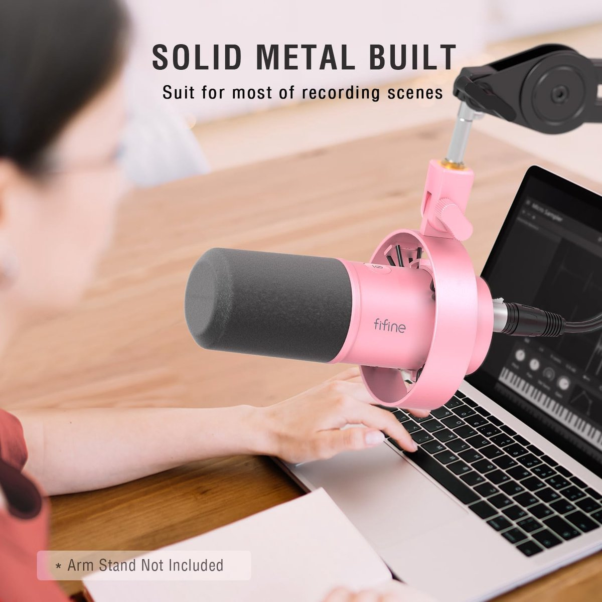 Une personne tape sur un ordinateur portable à côté d'un microphone rose avec un filtre anti-pop.