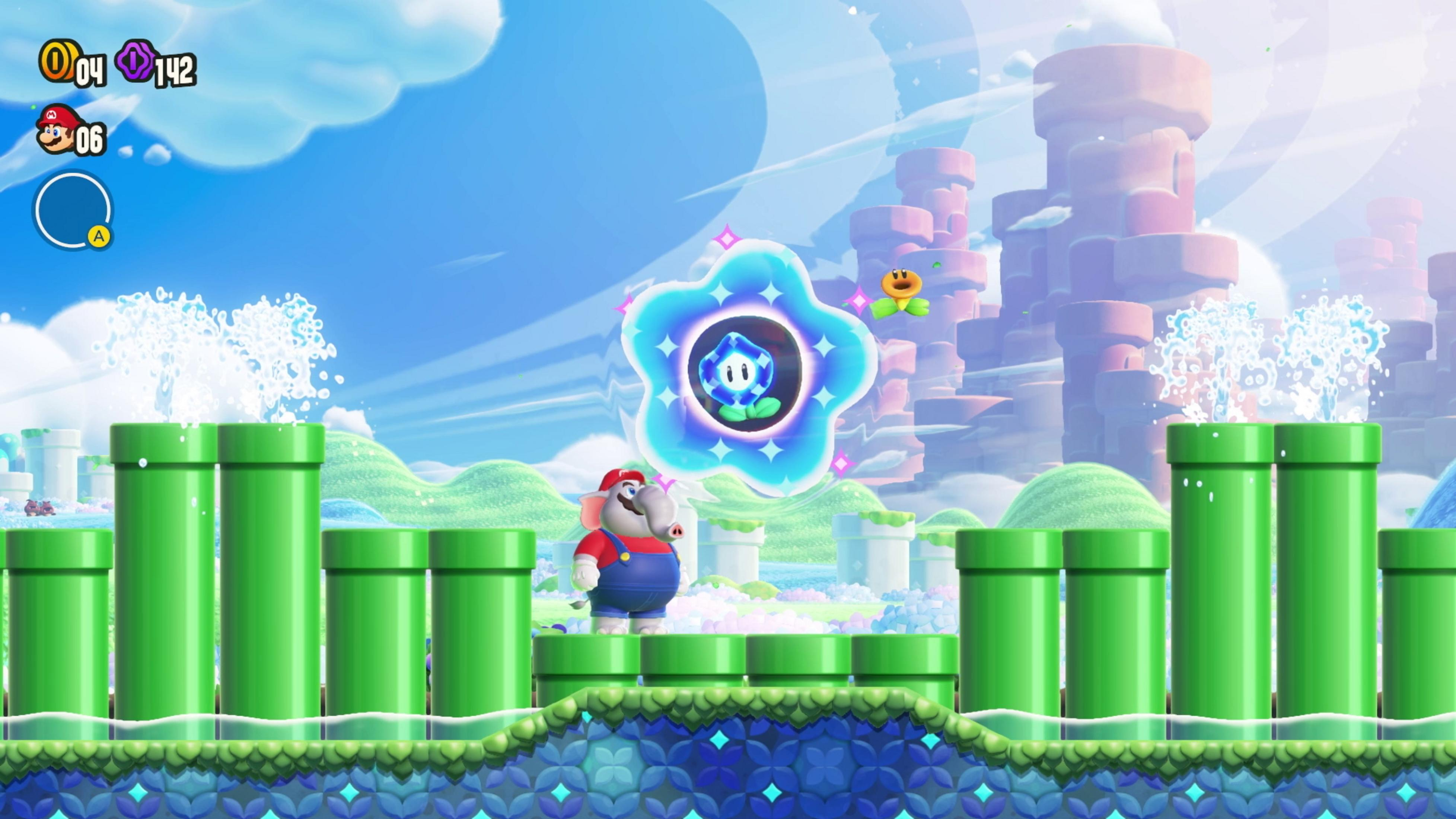 Mario elefante si trova su una piattaforma vicino a tubi verdi, con un gioiello blu nell'aria.
