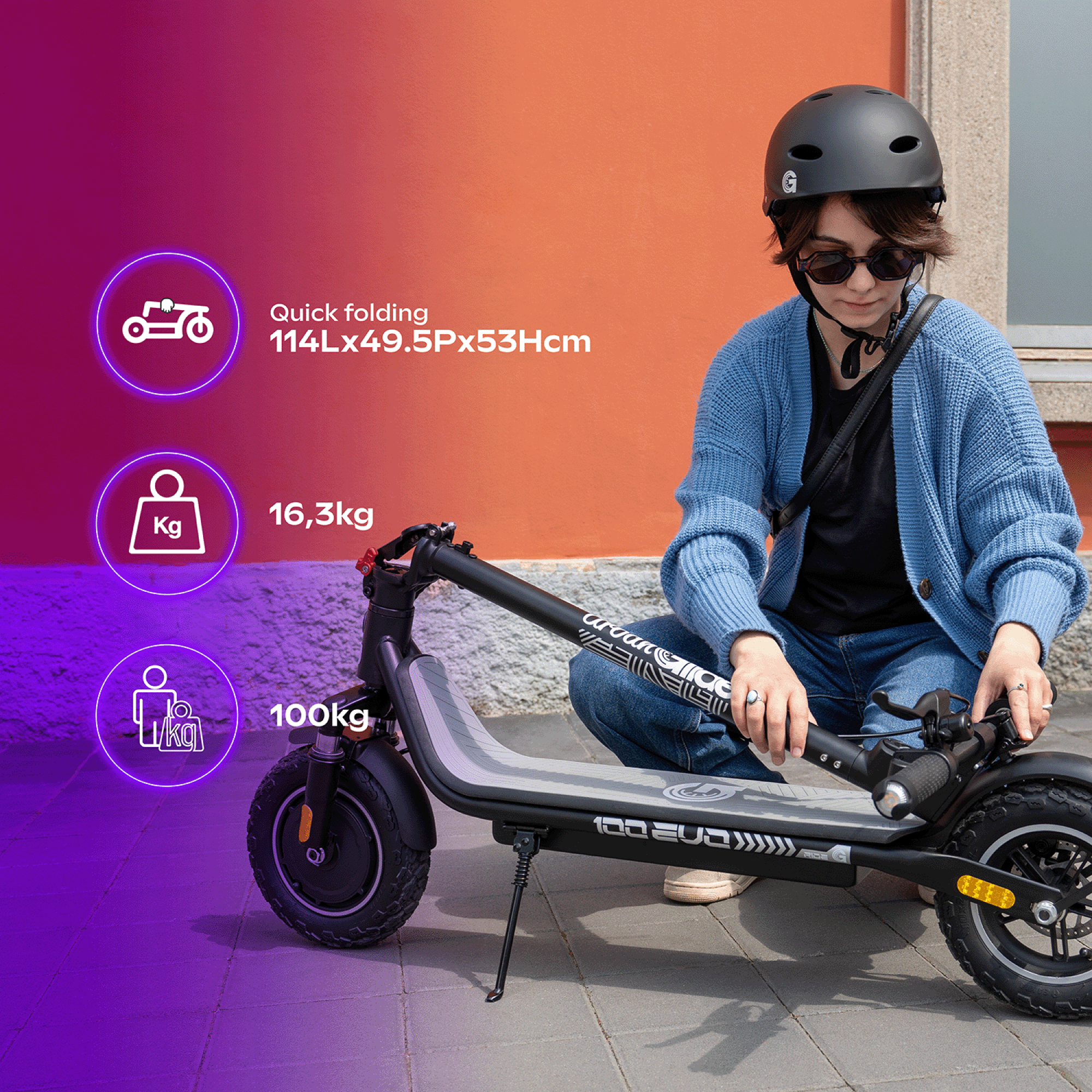 Una persona con casco y gafas de sol se arrodilla junto a un patinete eléctrico negro.