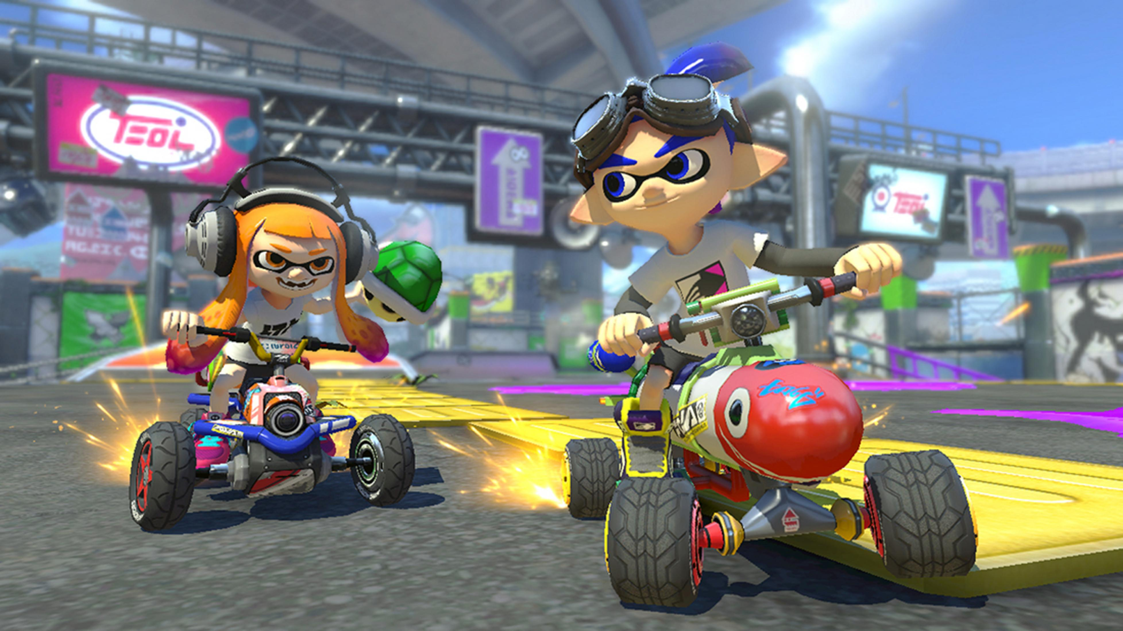 Due personaggi gareggiano con go-kart su una pista, un Inkling arancione con cuffie, un Inkling blu con occhiali.