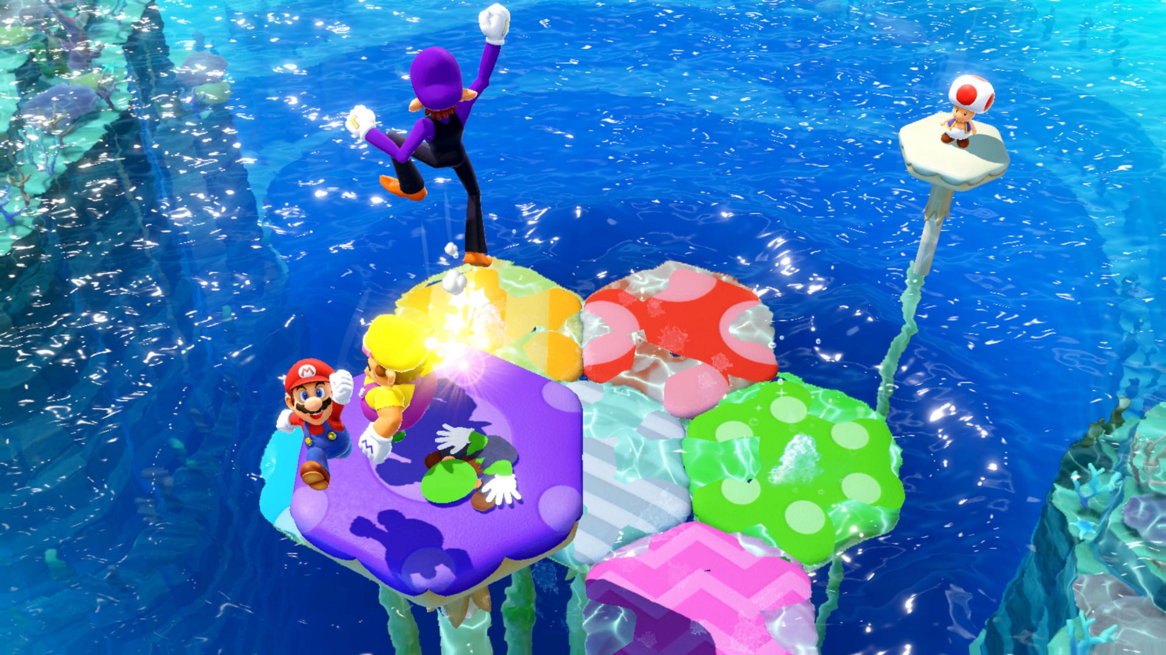 Mario, Wario, Luigi, Waluigi e Toad su piattaforme a fungo sopra l'acqua blu.