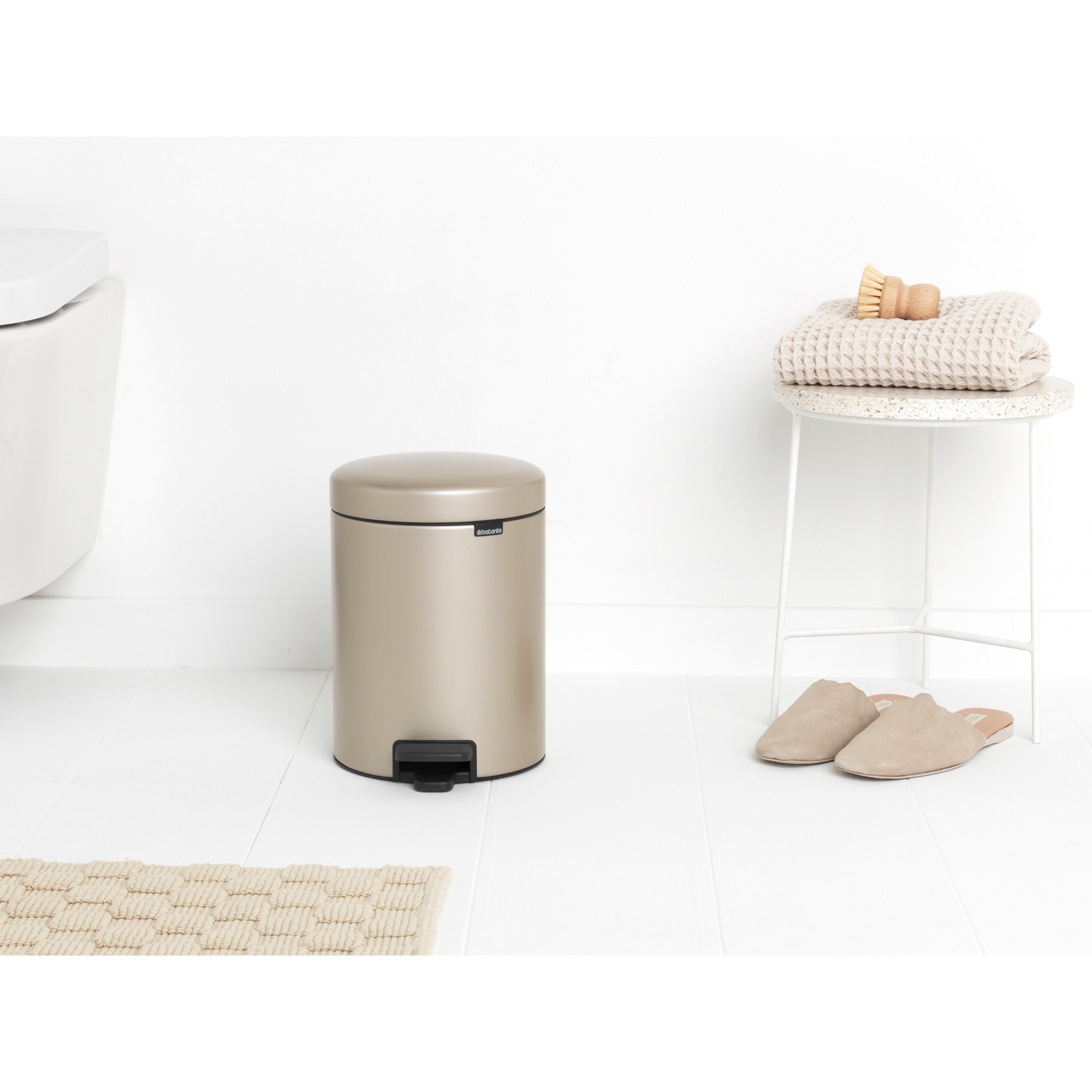 Een goudbruine pedaalemmer staat naast een toilet.