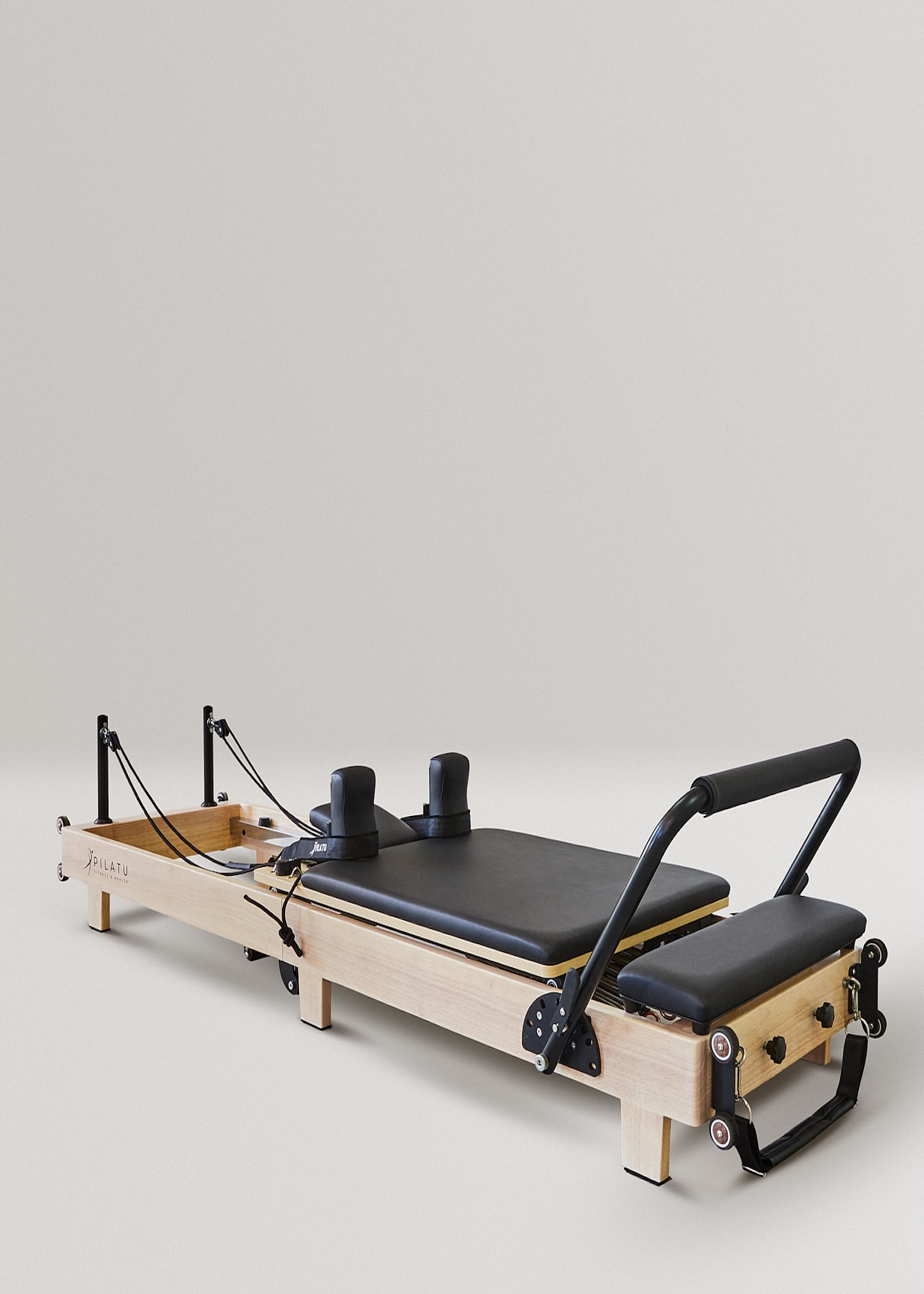Un reformer Pilates de madera con acolchado negro, correas y ruedas.