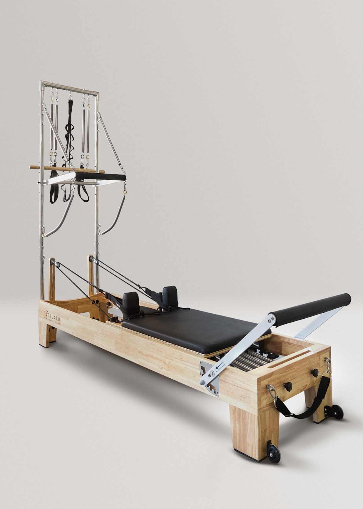 Un reformer de Pilates con marco de madera, colchoneta negra, resortes y correas.