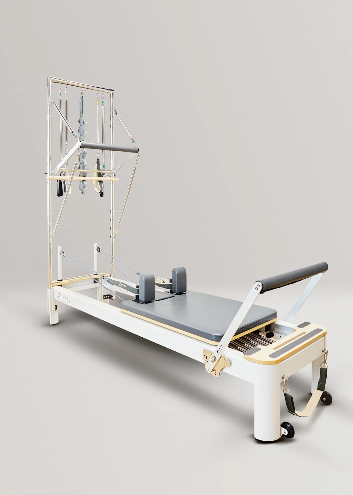 Un reformer de Pilates blanco con carro gris, barras y cuerdas sobre fondo gris.