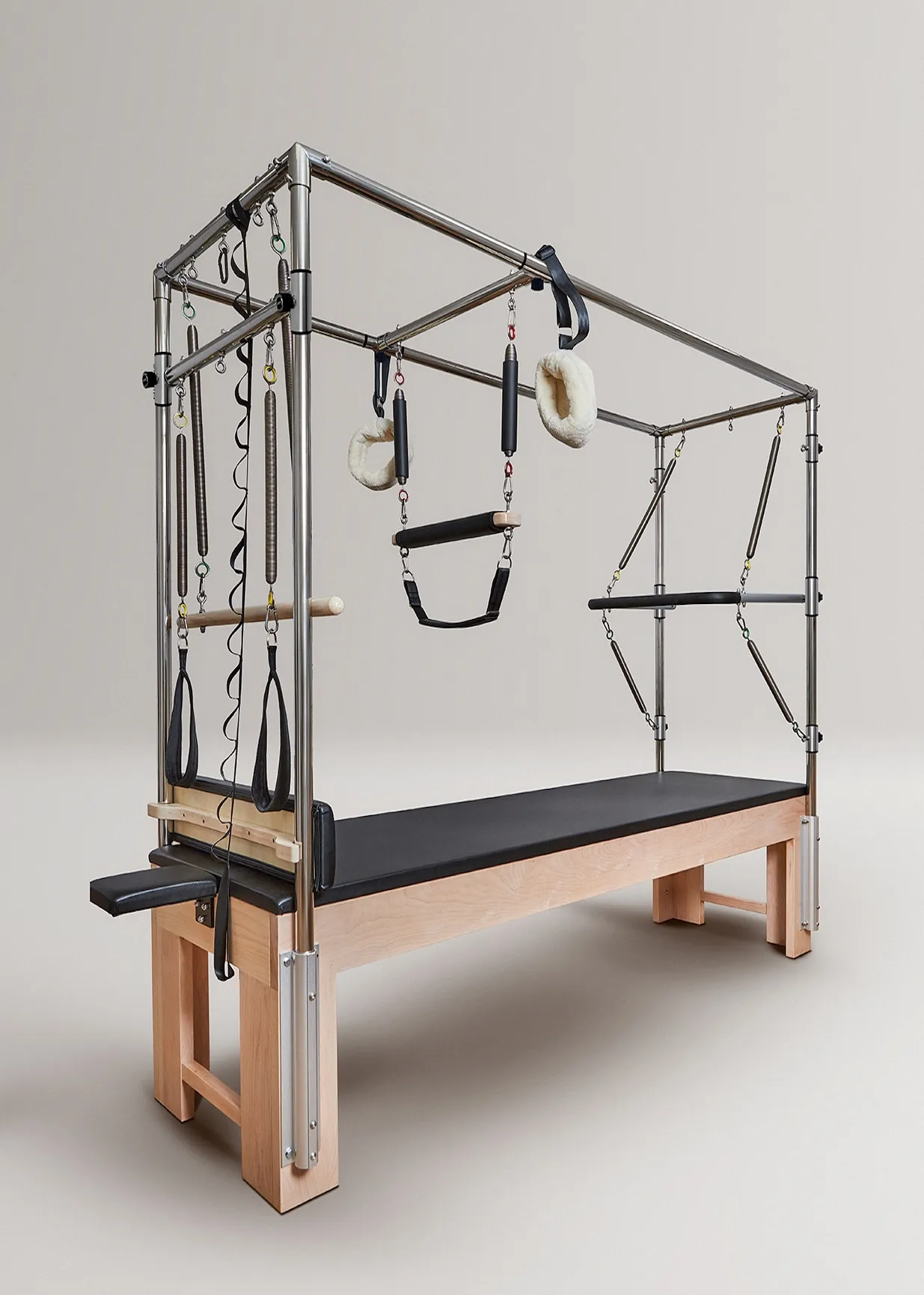 Un reformador de Pilates plateado con marco de madera, colchoneta negra y resortes.