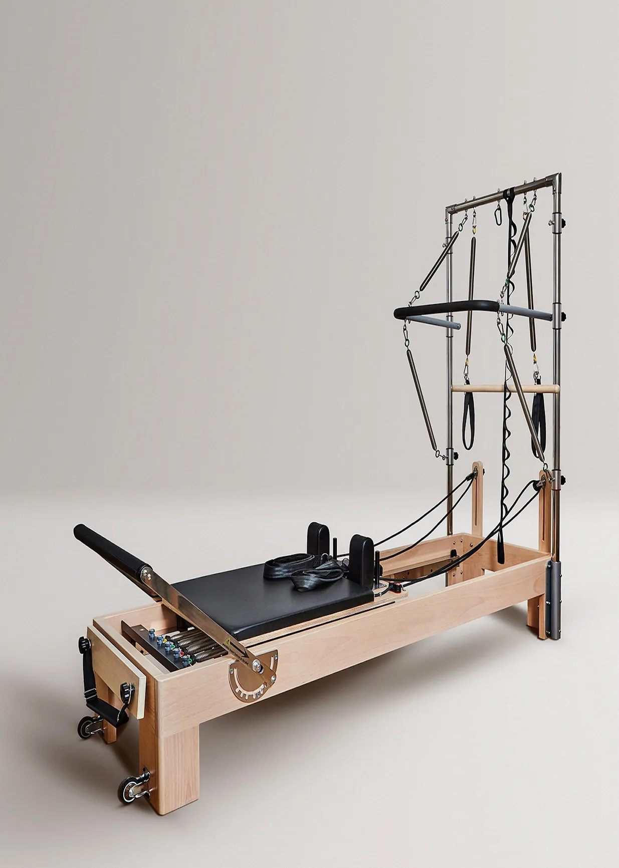 Un reformer de Pilates de madera con acolchado negro y resortes metálicos.