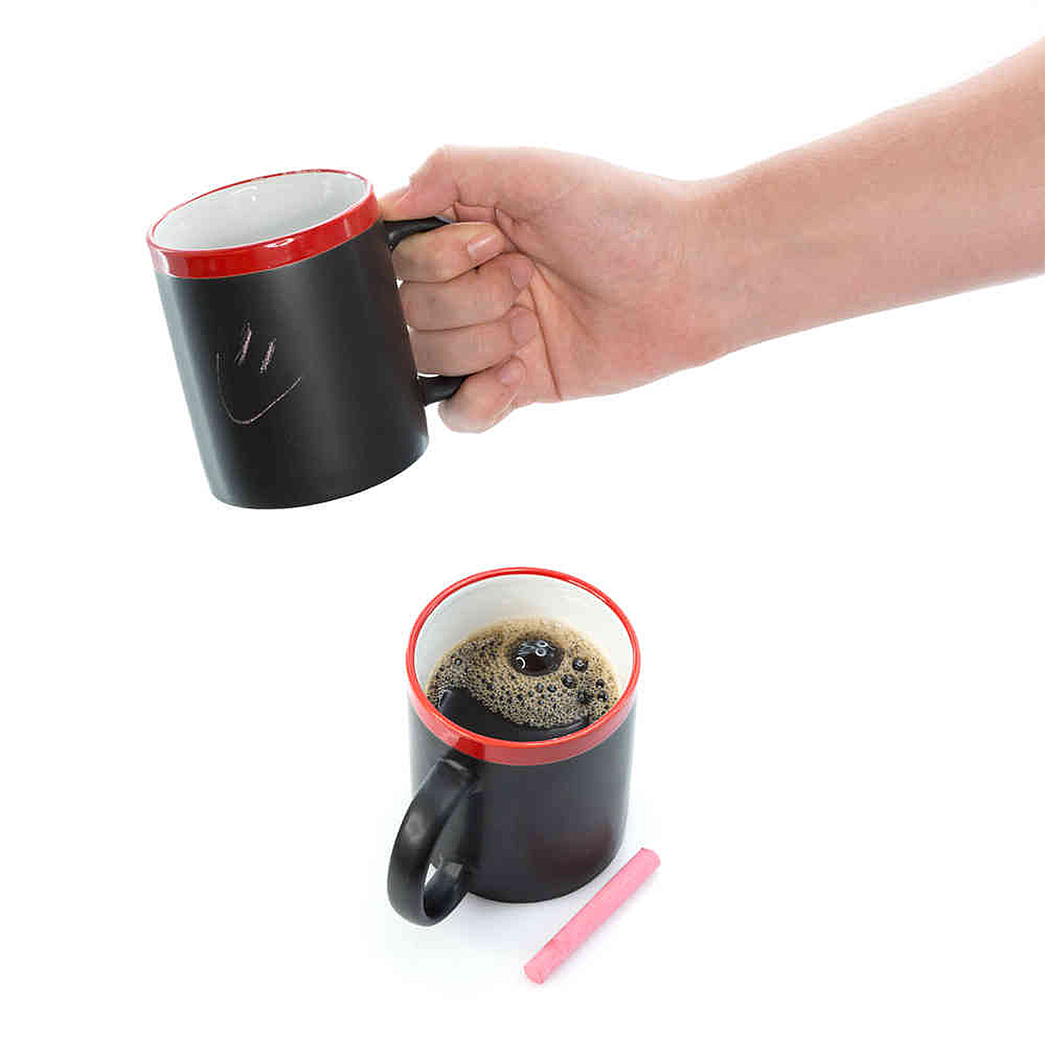 Mano sujetando taza negra con borde rojo; taza llena y tiza cerca.