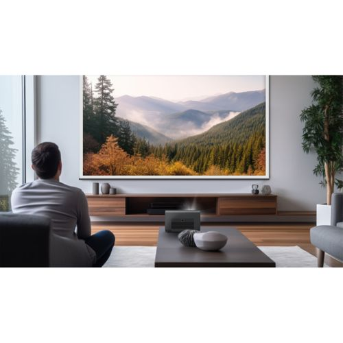 Mann schaut auf Projektorleinwand mit Berglandschaft, moderner Wohnraum.