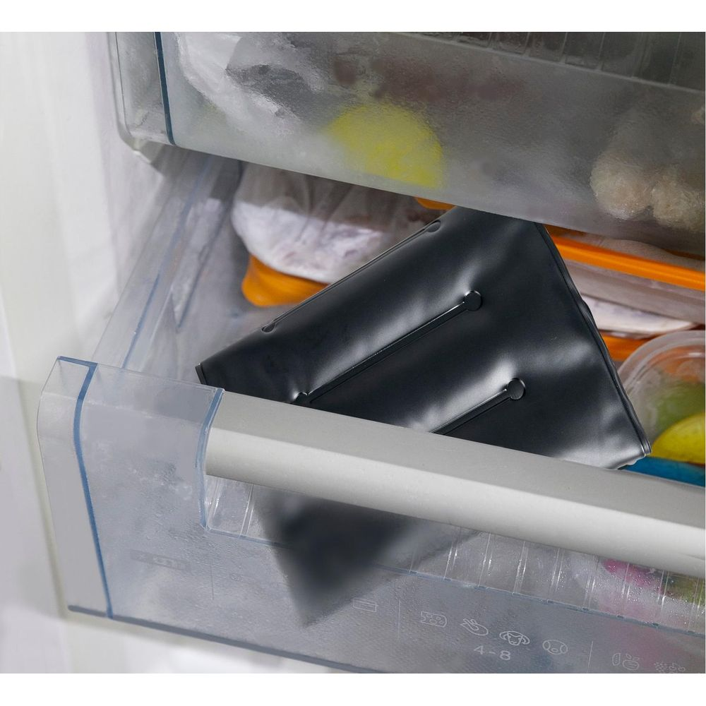 Una borsa del ghiaccio nera si trova in un cassetto del congelatore accanto a cibi surgelati.