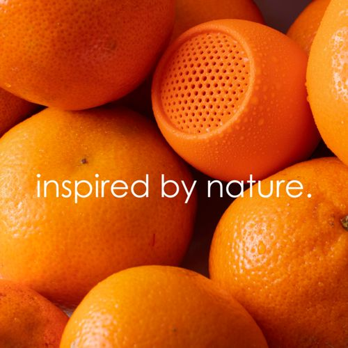 Un haut-parleur orange en forme d'orange, entouré de vraies oranges. Texte 'inspiré par la nature'.