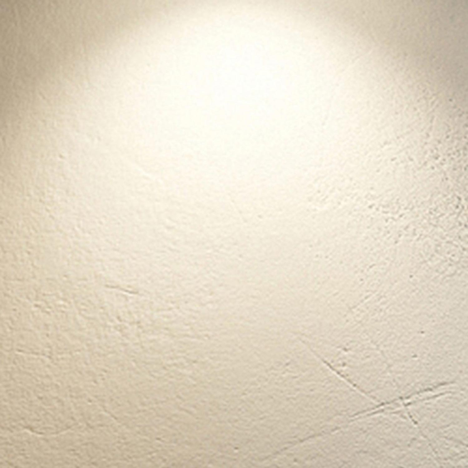Un muro di colore chiaro con texture sottile e un punto luminoso.