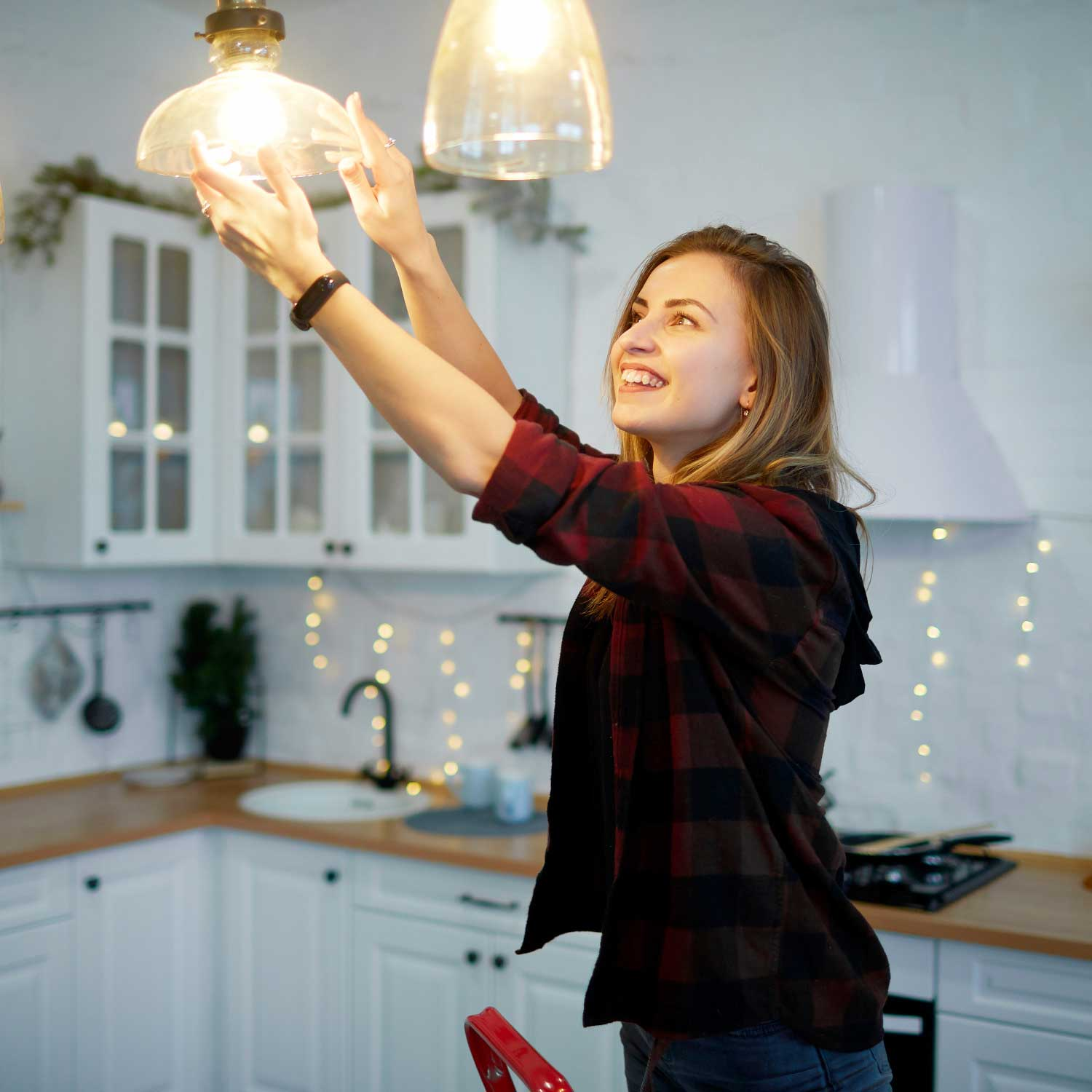 Una donna cambia una lampadina in cucina.
