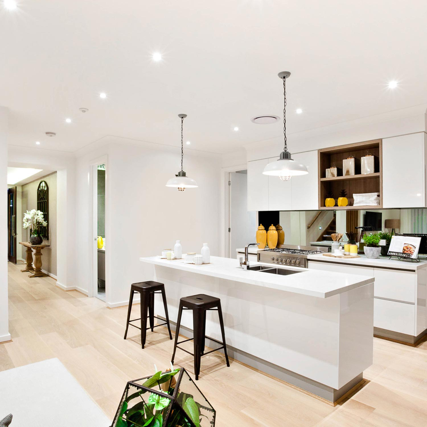 Moderna cucina bianca con isola, sgabelli e pavimenti in legno.