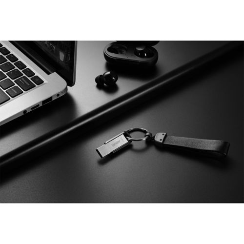 Un laptop, auricolari wireless e un'unità USB su un portachiavi giacciono su una superficie nera.
