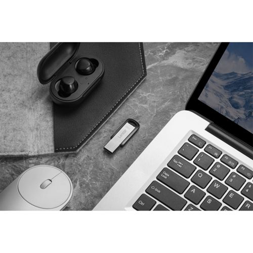 Un laptop, auricolari nella custodia, unità USB e mouse su superficie di marmo.