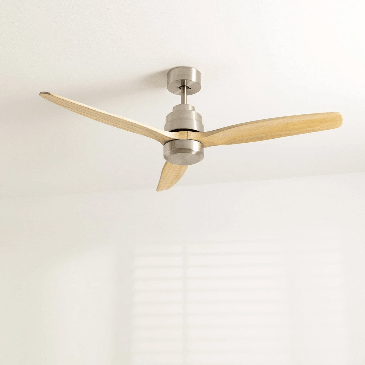 Ventilador de techo moderno con tres aspas de madera y carcasa metálica.