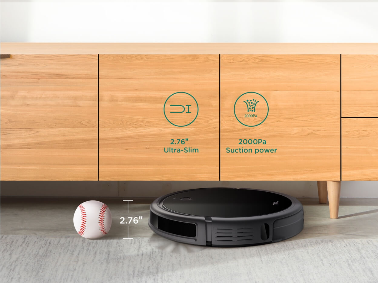 Czarny robot sprzątający obok piłki baseballowej pod drewnianą szafką.
